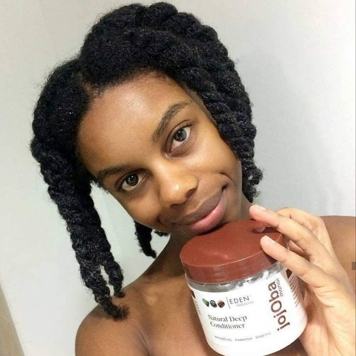 A person holding the tub of deep conditioner under their chin