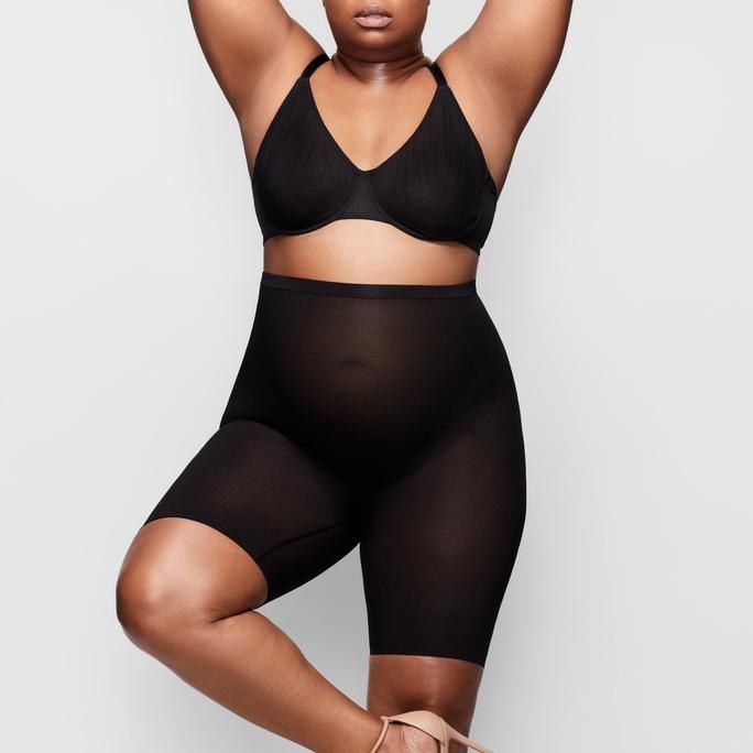 plus size model wearing a black bra and black shaping shorts in sheer black