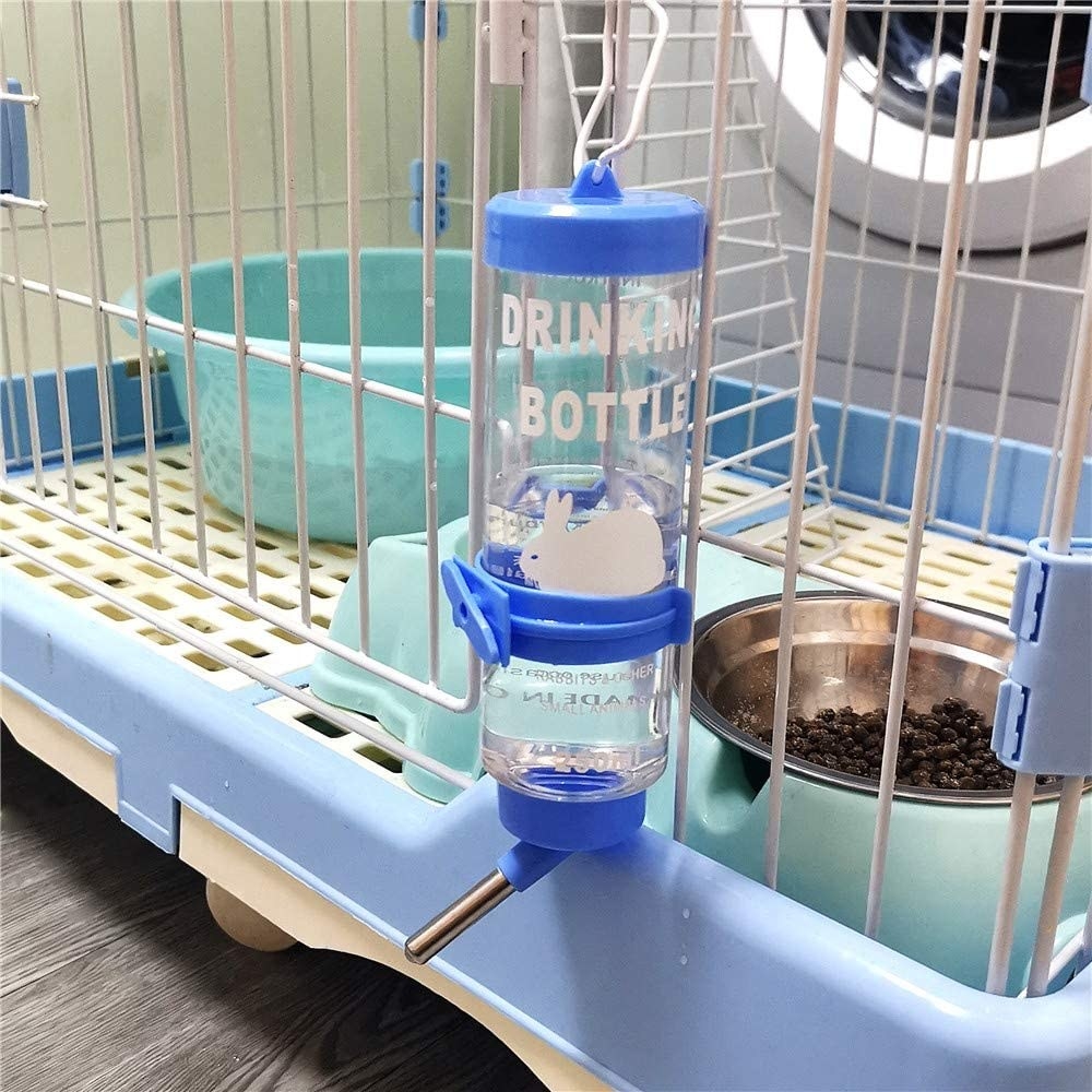 A clear water bottle with blue accents hanging from a pet cage