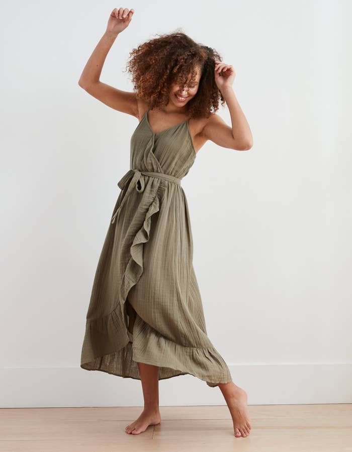 model in olive green wrap midi dress with belt tie, spaghetti straps, and ruffle down the front and along bottom edge