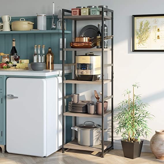 A tall shelving unit with square wooden shelves and a metal frame. There is enough space between each shelf to hold several large pots, sets of dishes, kitchen tools, etc. 