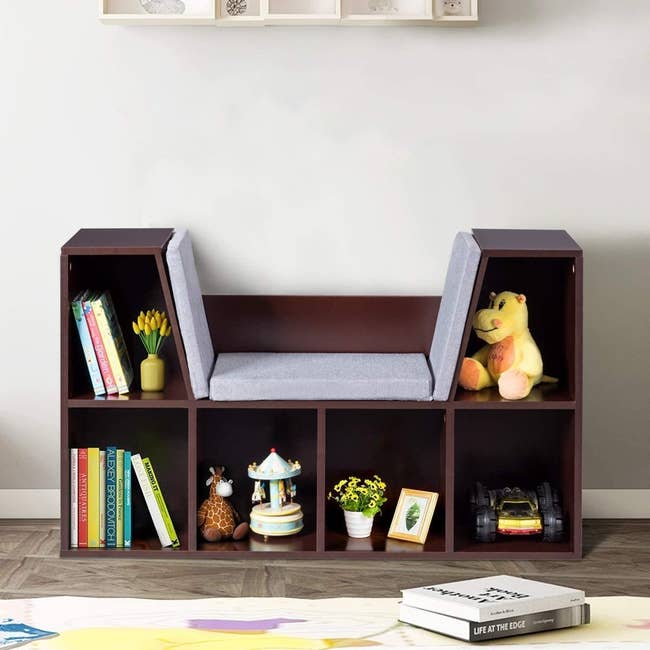 A five-shelf bookcase with a padded seat in the center 