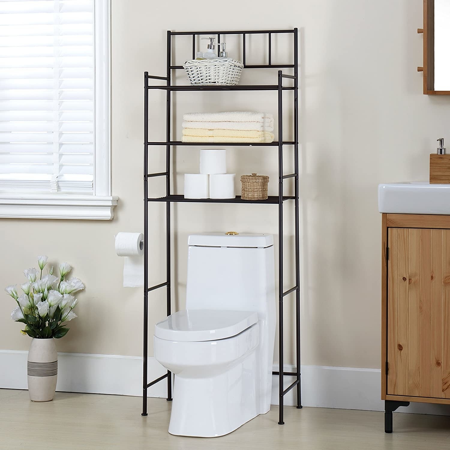 A minimalist shelving unit made of thin black pipes. It has three shelves that are high enough to go above the toilet tank. 
