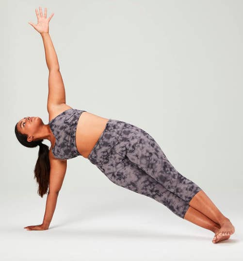 Model wears black tie-dye printed crop leggings while completing a yoga pose
