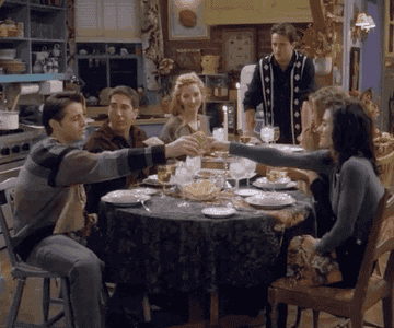 GIF of the Friends cast sitting at Monica&#x27;s dining room table having dinner.
