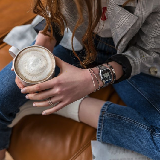 A person wearing the watch holding a cup of coffee