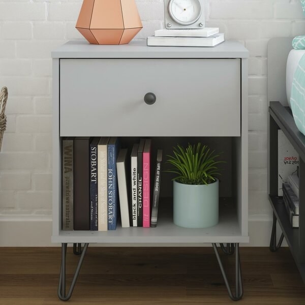 The grey nightstand with one drawer and one open shelf