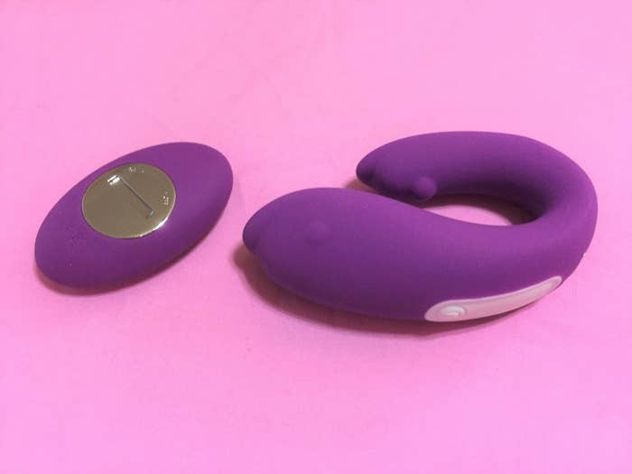 purple vibe shaped like dolphin bending in a u-shape next to small remote 