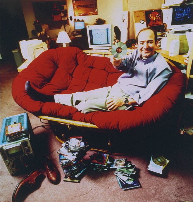Jeff Bezos on a couch holding a CD