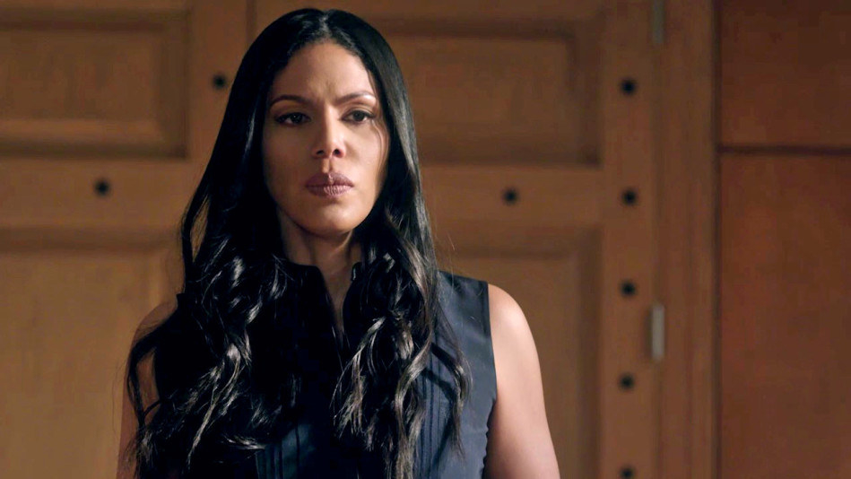 Merle Dandridge stands in the center of a room with a slightly tense facial expression