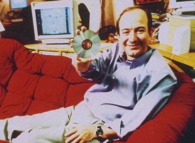 A closeup of Jeff Bezos on a couch holding a CD