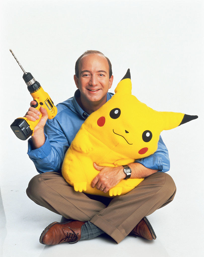 Jeff Bezos holding a drill and a Pikachu stuffed animal