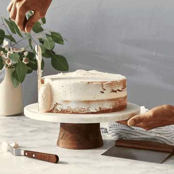 A gif of a person rotating the cake stand to frost a cake