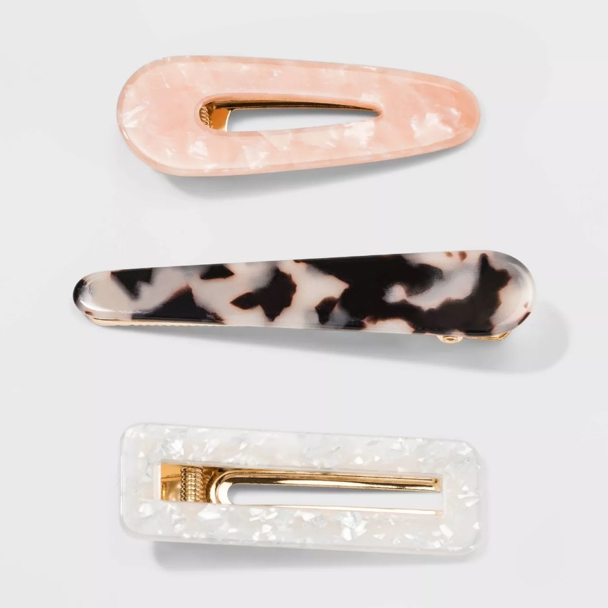 a pink resin clip, a marbled brown and white clip, and a white resin clip