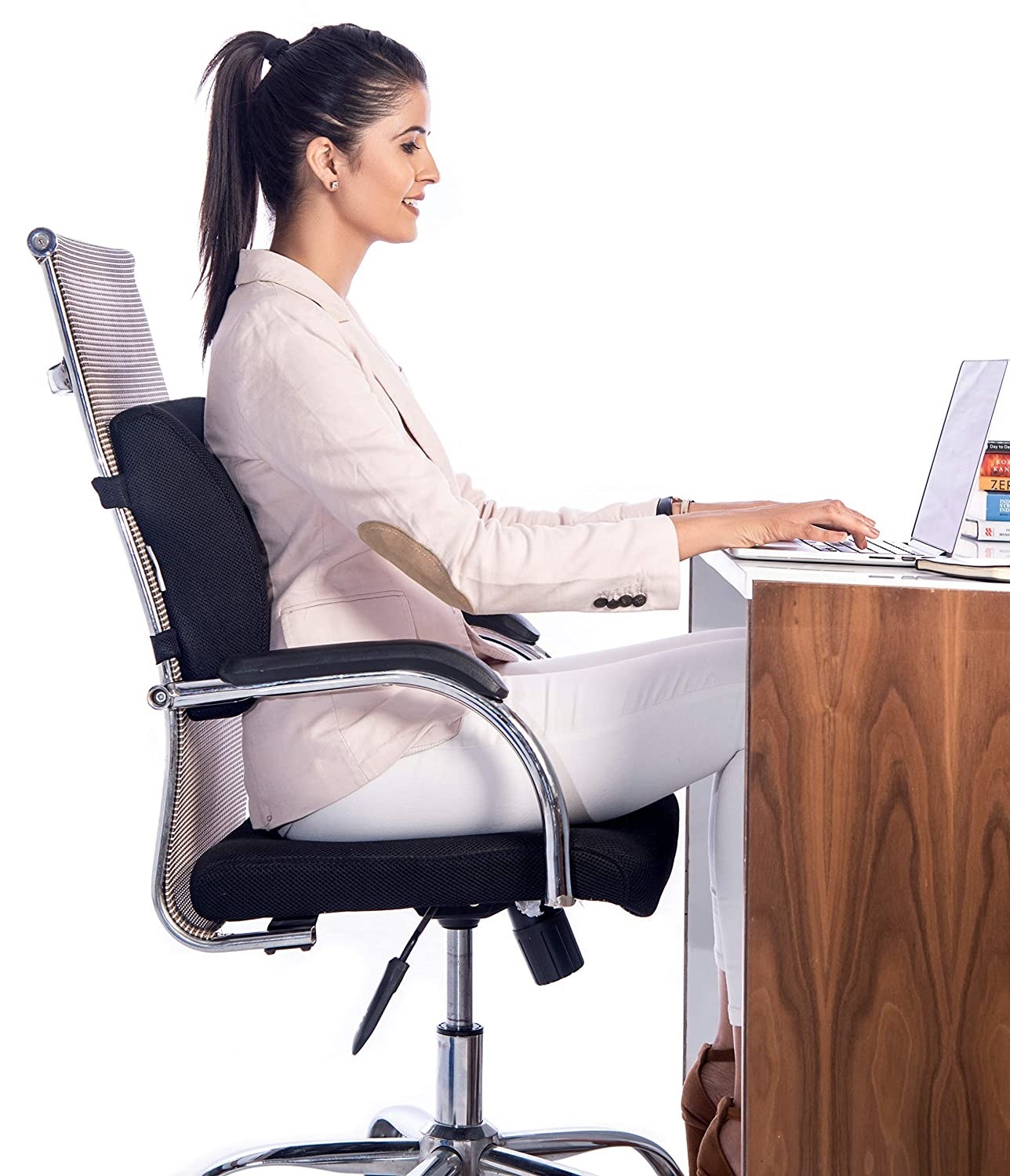 A woman using a laptop while sitting on a chair with the back cushion attached to it