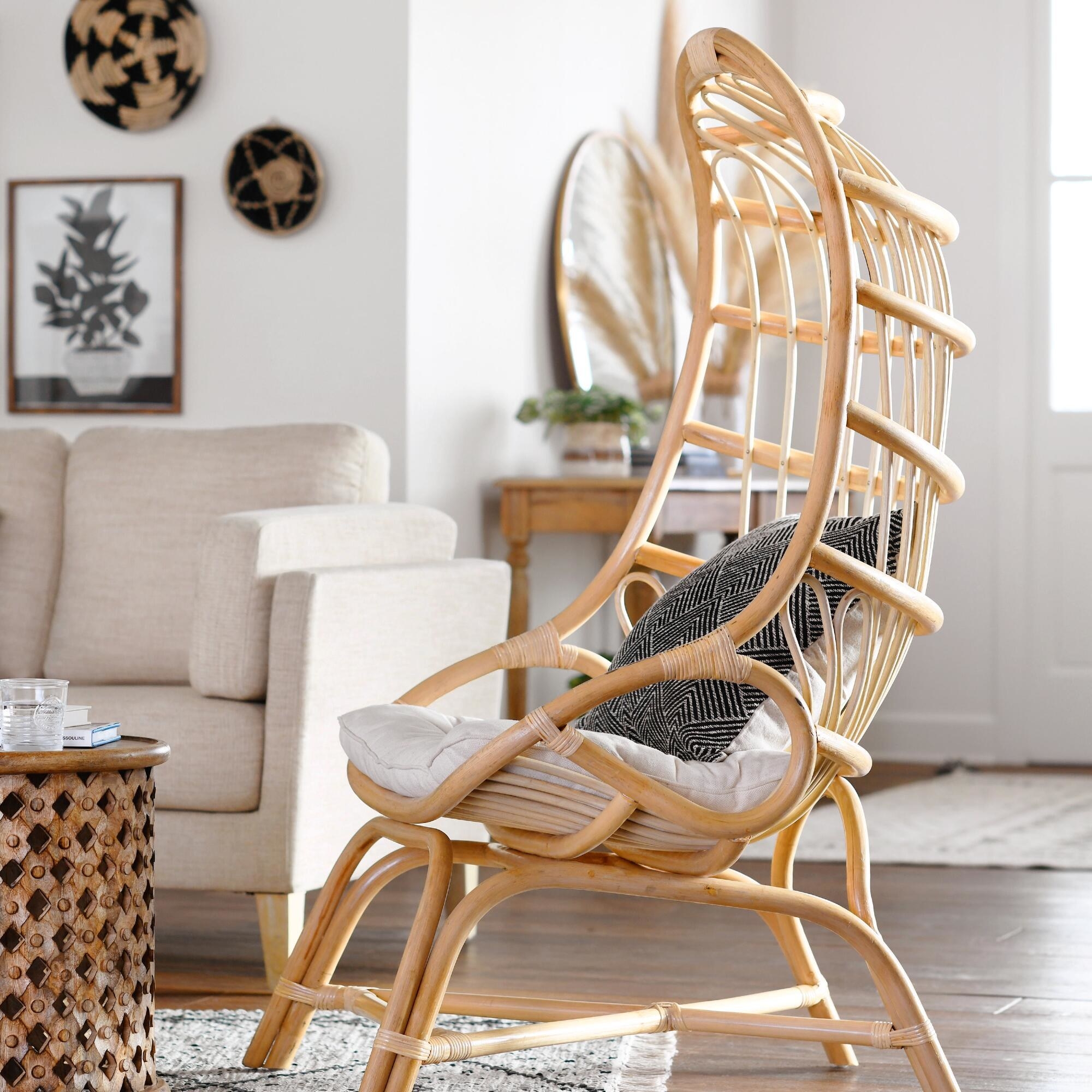 The cocoon chair made out of wood with a curved back design and a cushion and pillow inside