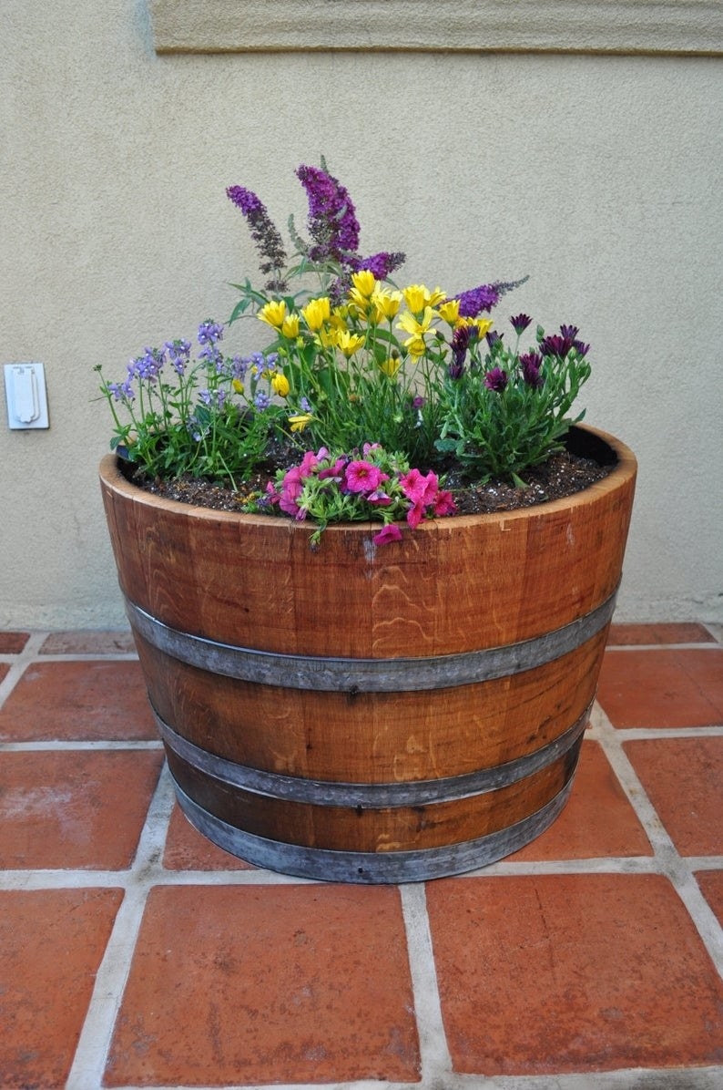 The half planter wine barrel with flowers and soil inside