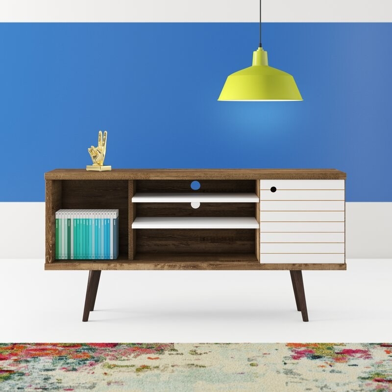 A brown wooden stand with three open shelves and one shelf closed with a white door. it has four brown wooden legs.