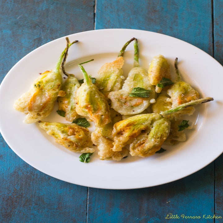 Plated fried squash blossoms filled with ricotta on a tabletop.