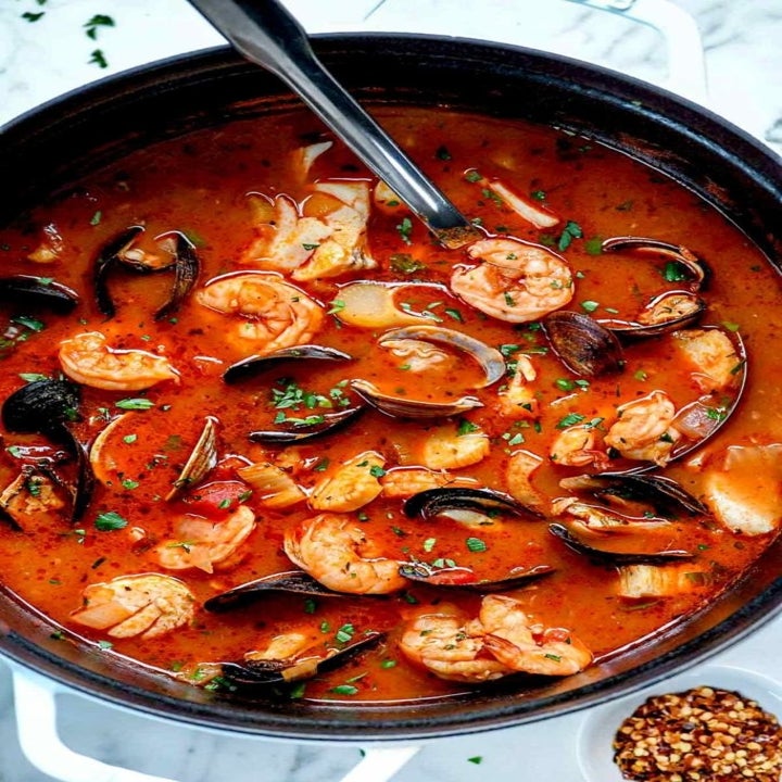 A pot of seafood cioppino with shrimp, mussels, and scallops in a tomato broth.