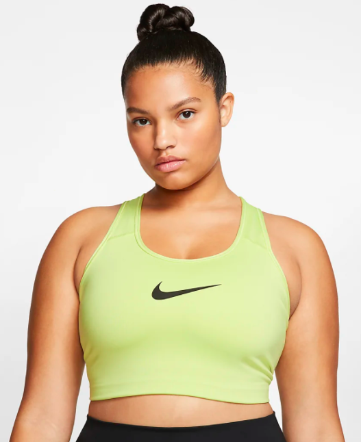 Model wears lime green Nike medium-support sports bra with black leggings