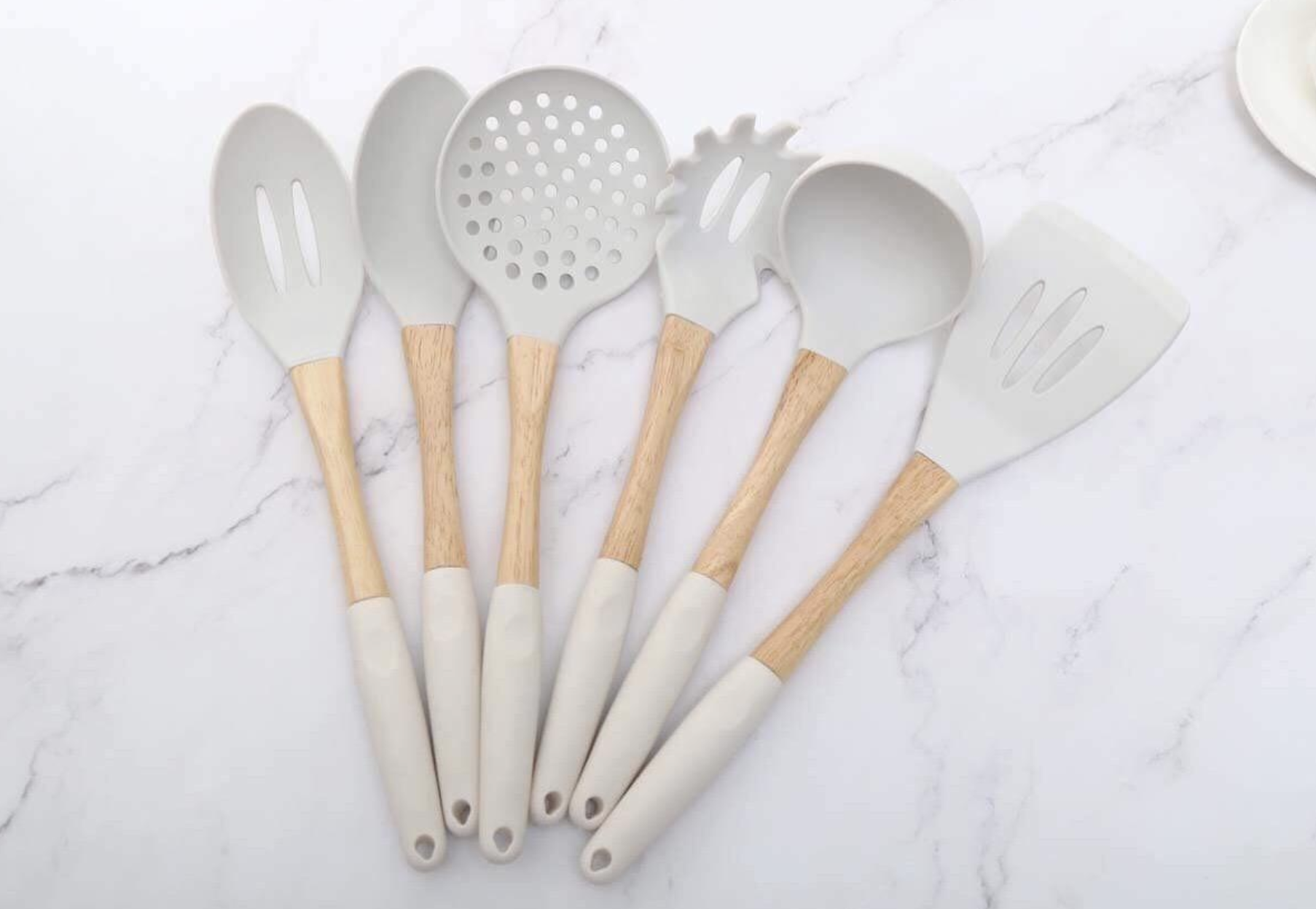 Reviewer image of the silicone utensil set laid out. The handle is a pretty wood with a matching silicone on the ends for cushion.
