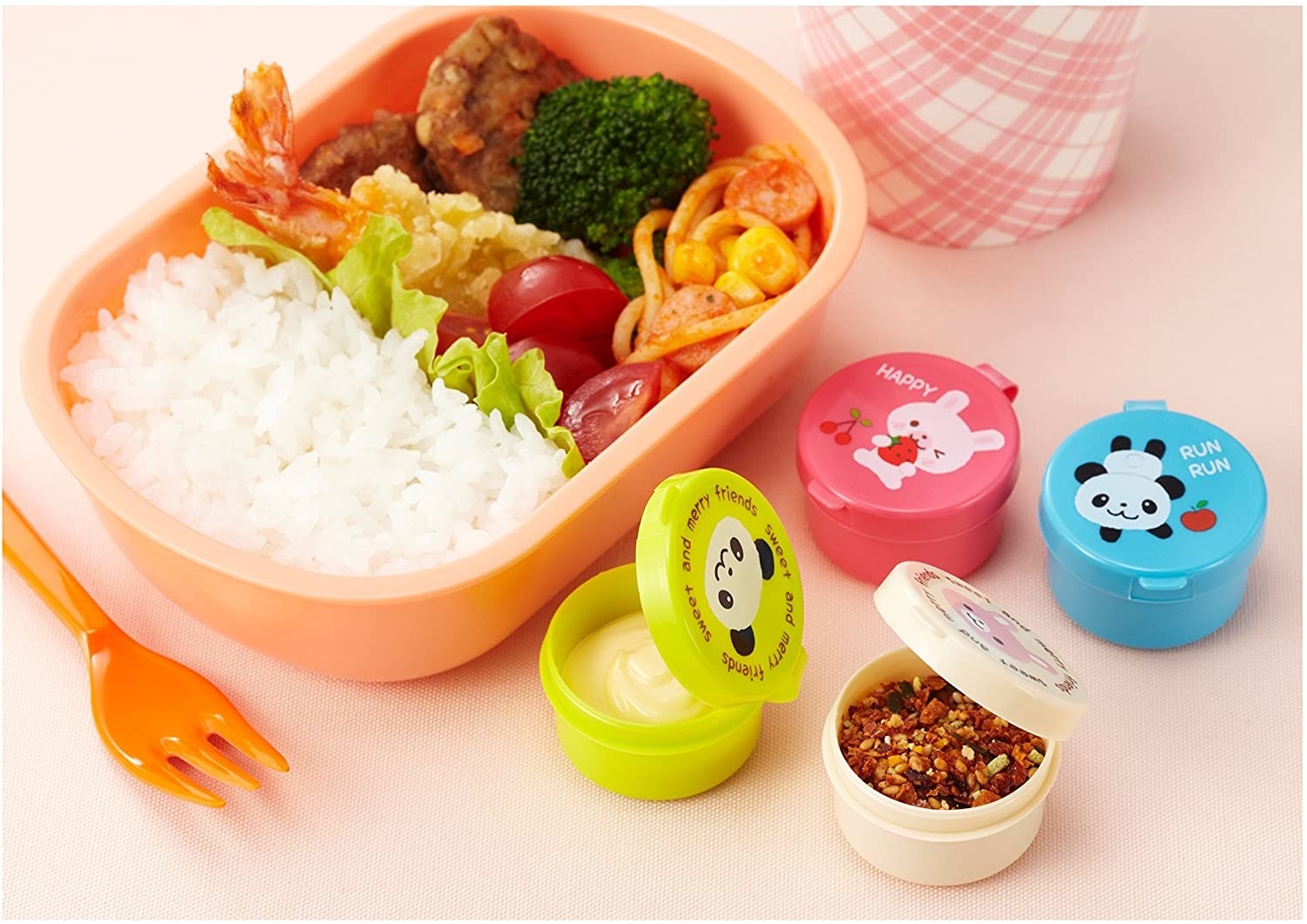 Four condiment holders next to a bento box of rice and stir fry
