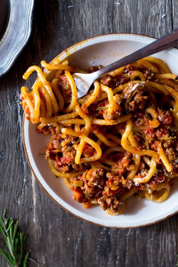 A bowl of thin, long noodles topped with meaty ragu sauce.