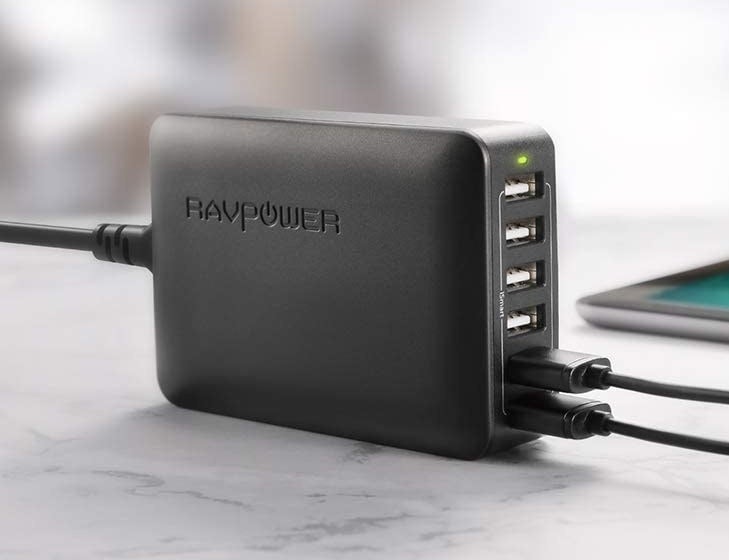 The charging port in black with two USBs plugged into it and four open spots on a table