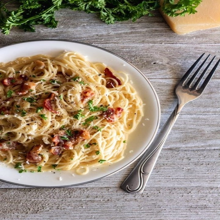 A plate of spaghetti carbonara tossed with bacon in a creamy cheese sauce.