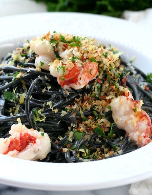 A bowl of squid ink spaghetti with buttery breadcrumbs and lobster meat.