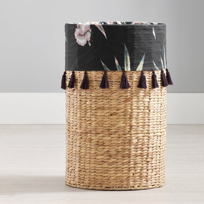 Wicker hamper with the liner draped slightly over to reveal a floral print and little tassels. 