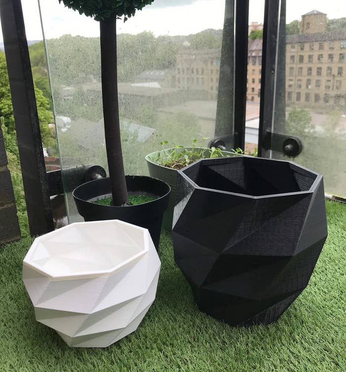 One white and one black 3D-printed planter without any plants inside