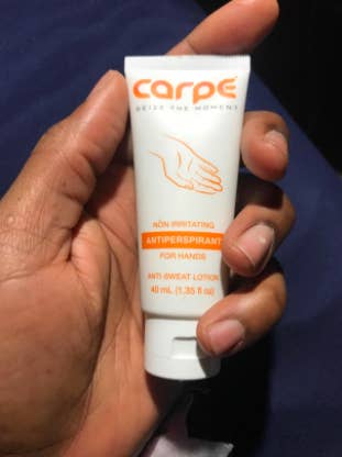 reviewer's dry looking hand holding the tube of cream
