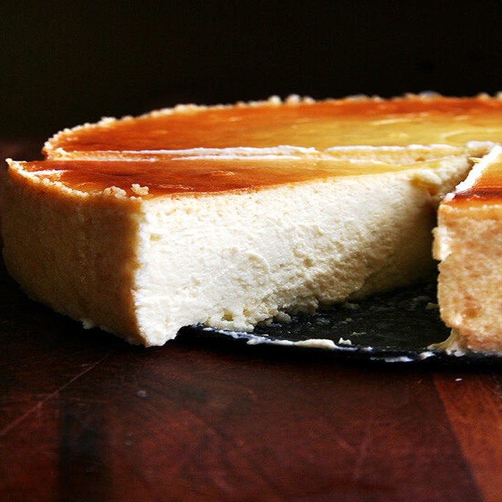 A slice of lemon ricotta cheesecake on a black platter.