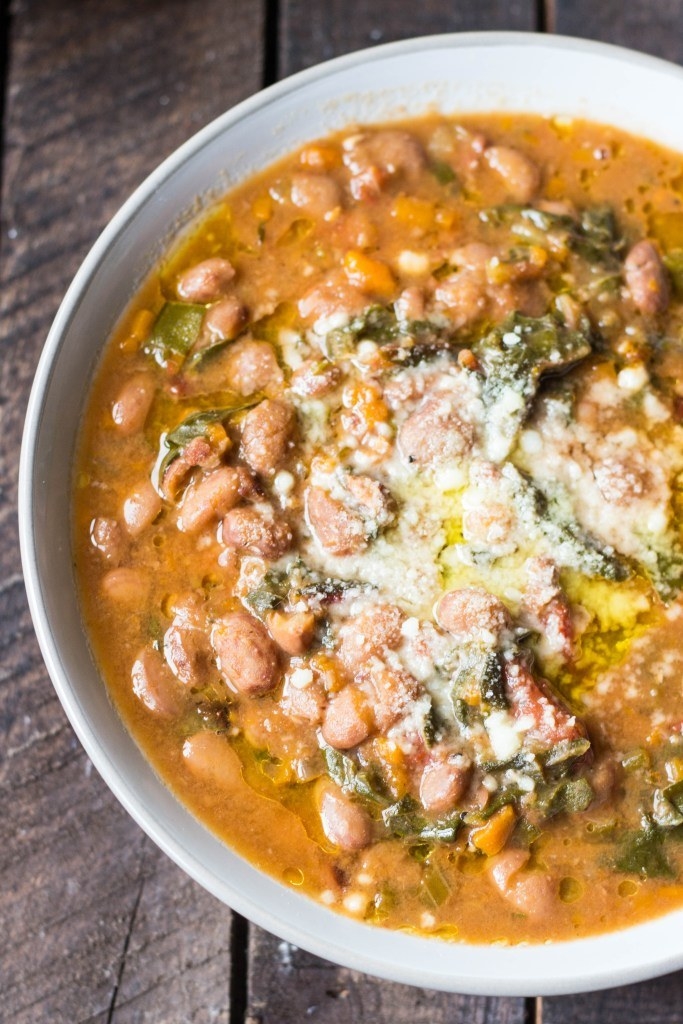 A bowl of thick Tuscan ribollita with beans, veggies, diced tomatoes, and a lot of Parmesan cheese.