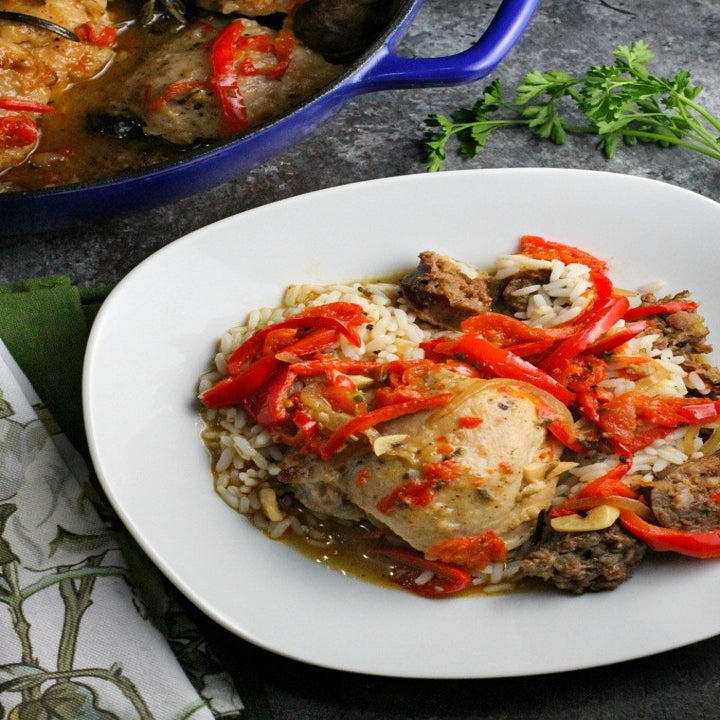 Chicken scarpariello, peppers, and sausage tossed with rice in a bowl.