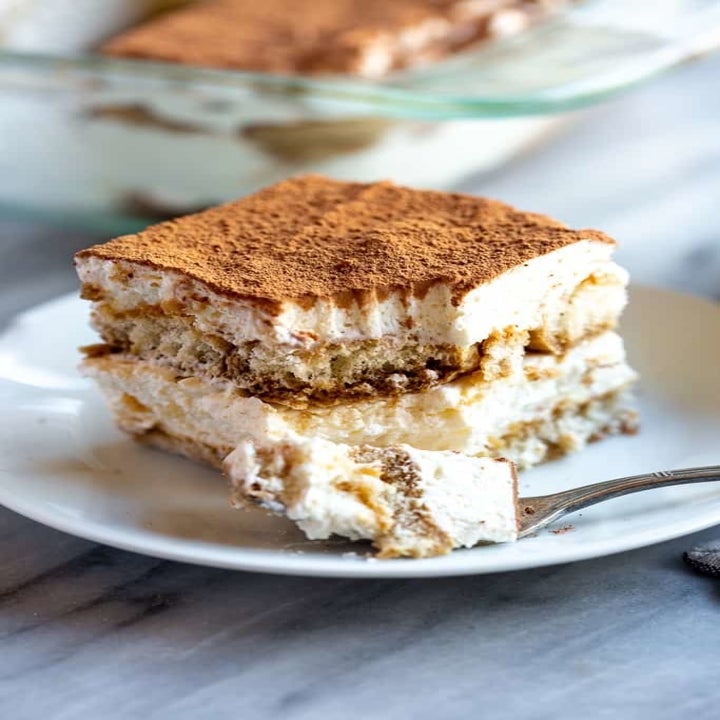 A fork taking a slice of fluffy, light tiramisu.