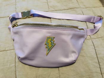 a lavender fanny pack with a lightning bolt patch on it