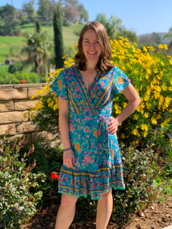 A reviewer wearing the dress in teal with pink and yellow flowers
