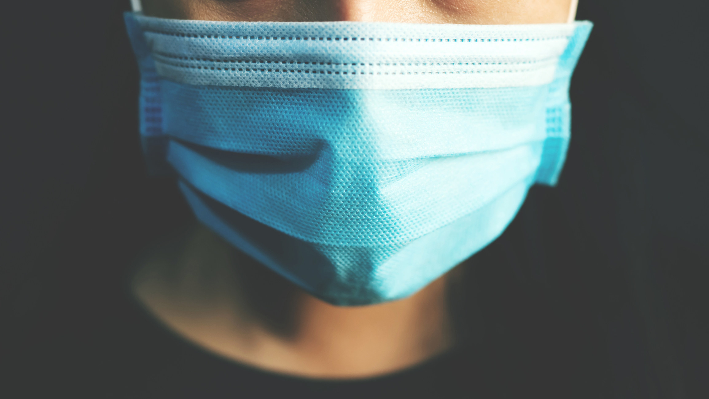 close up of a person wearing a blue surgical mask