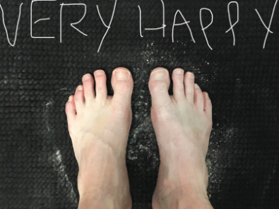 A reviewer with their feet covered in the powder and the words &quot;Very Happy&quot; written above them 