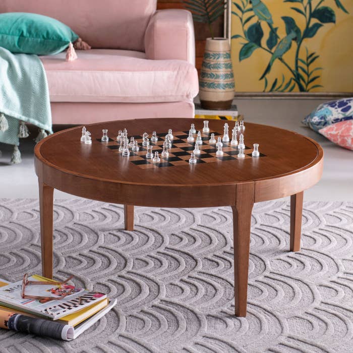 A round brown coffee table with a chessboard pattern on the tabletop