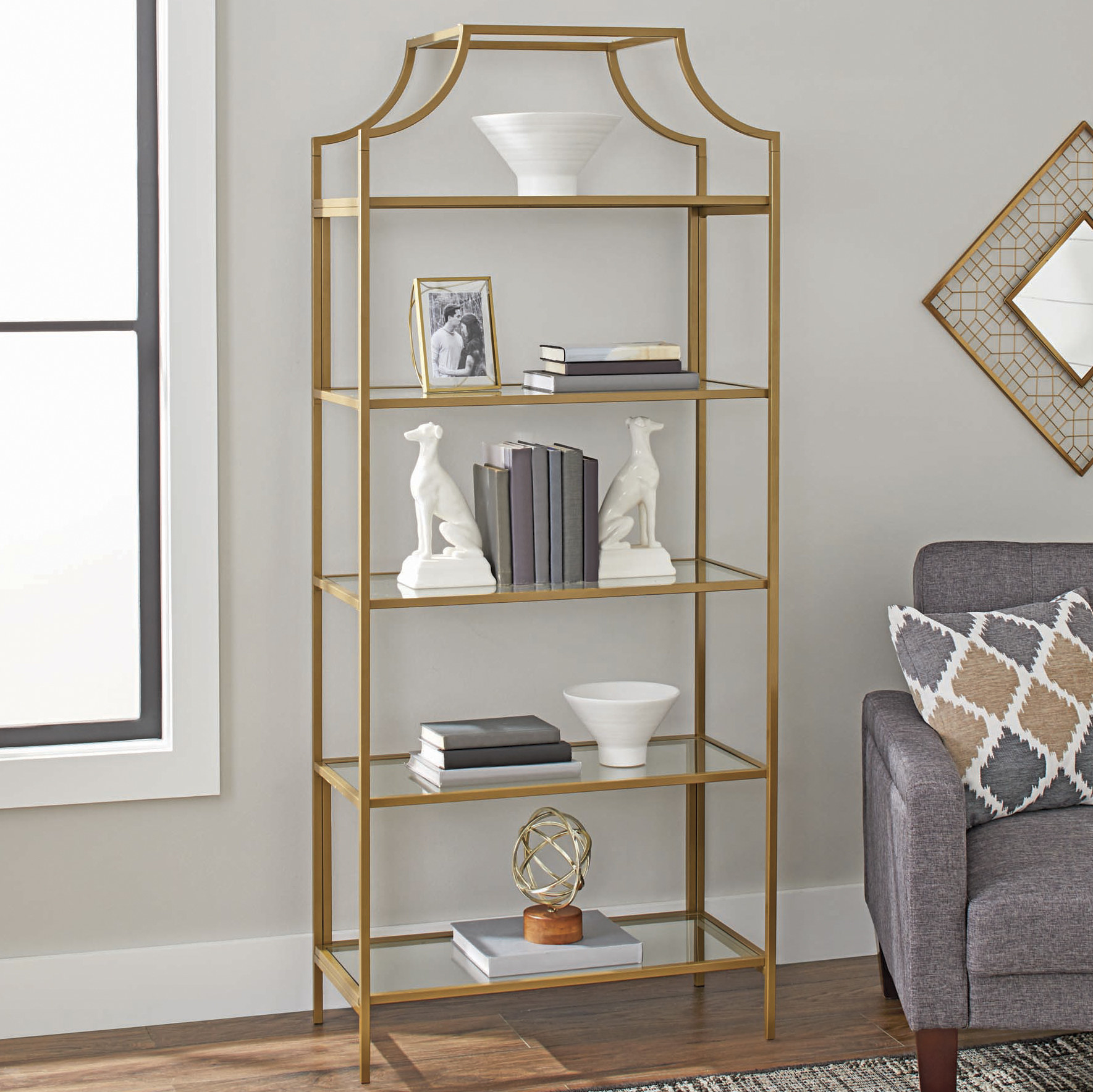 A gold-framed bookcase with five glass shelves