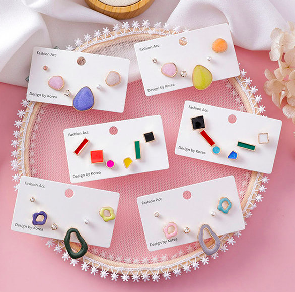 Colorful mismatched geometric earring packs arranged on a pink table