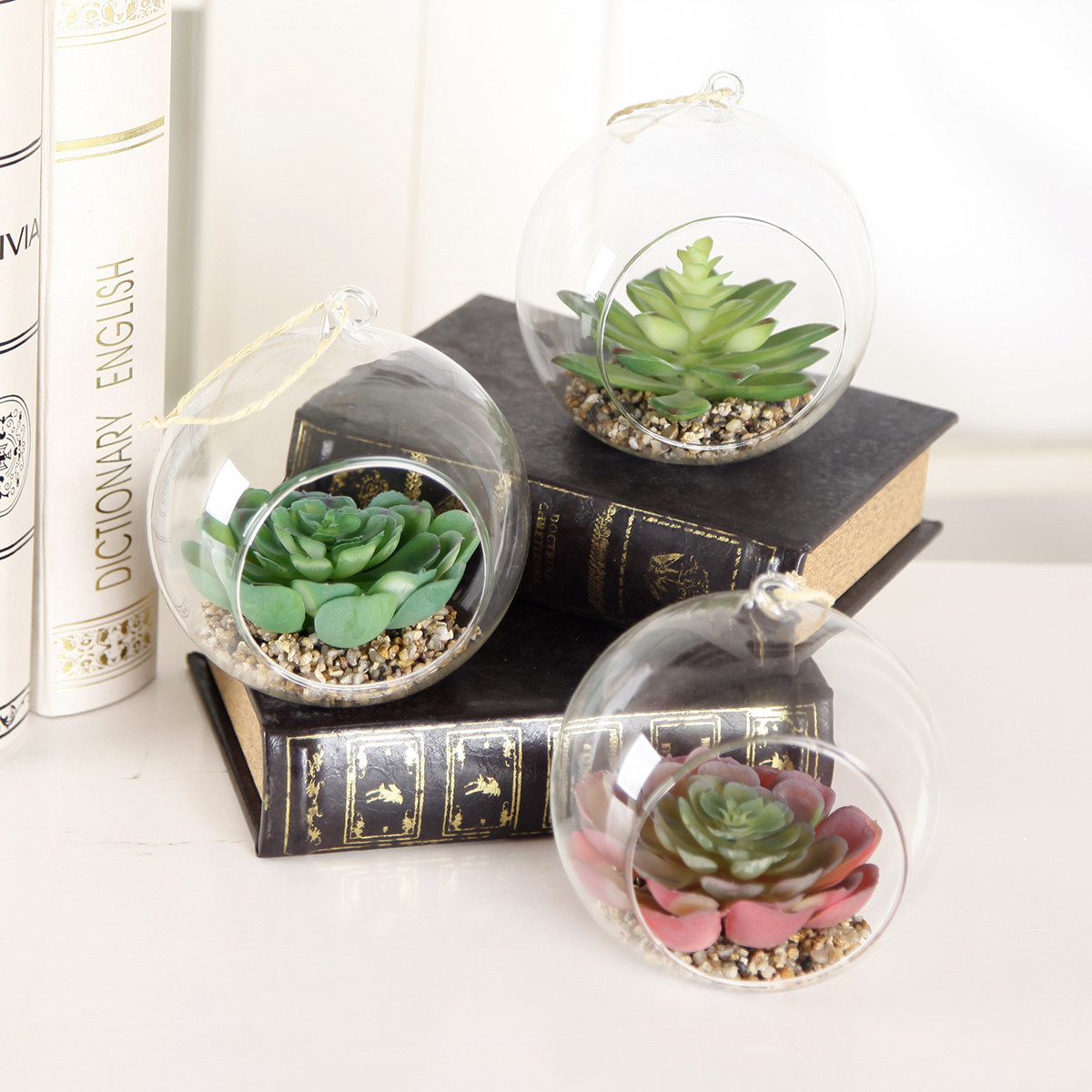 Three fake succulents in open round glass terrariums