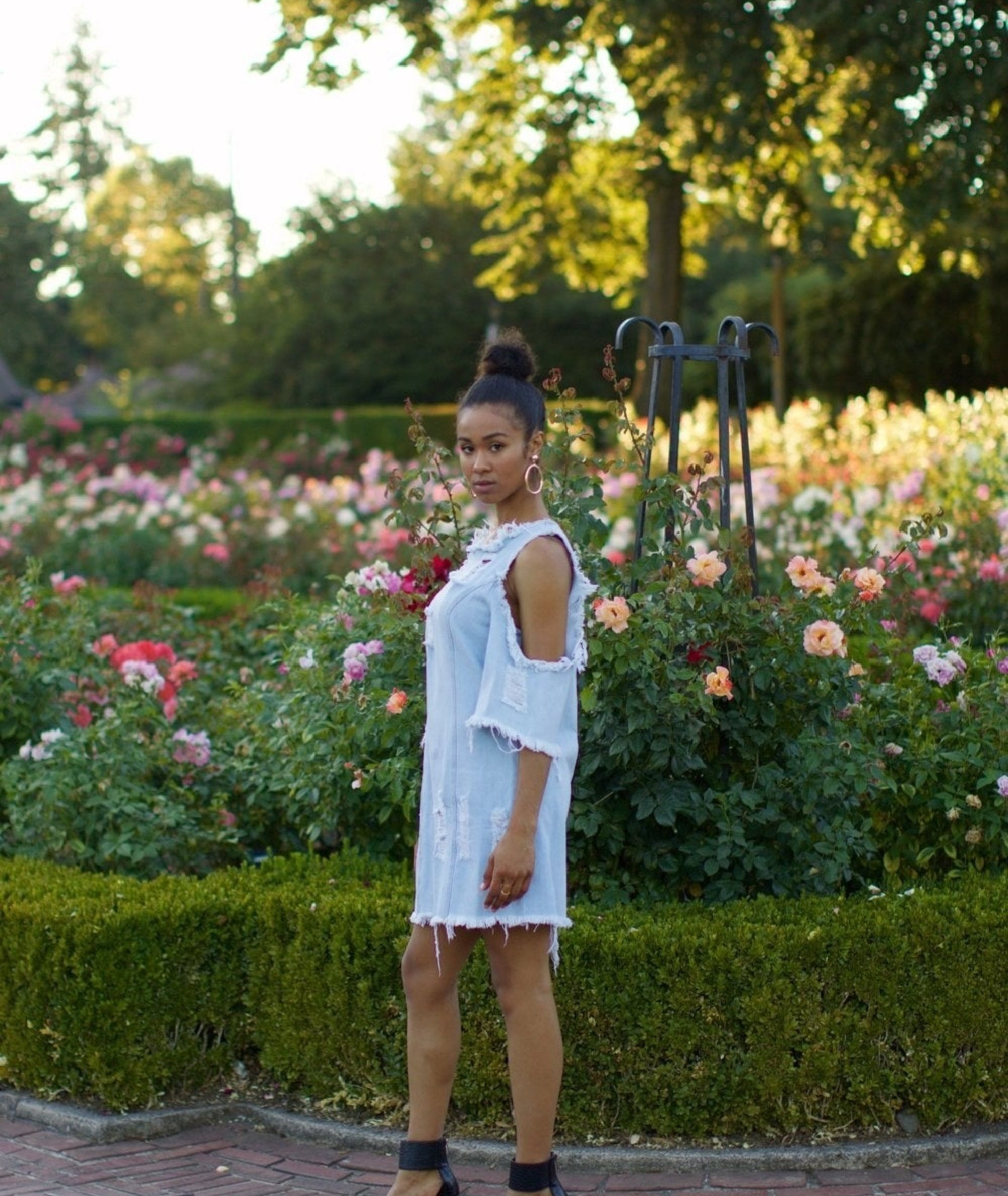 A model in the dress, which has cold-shoulder cut-outs, a high neck, frayed edges, and is intentionally distressed in several places