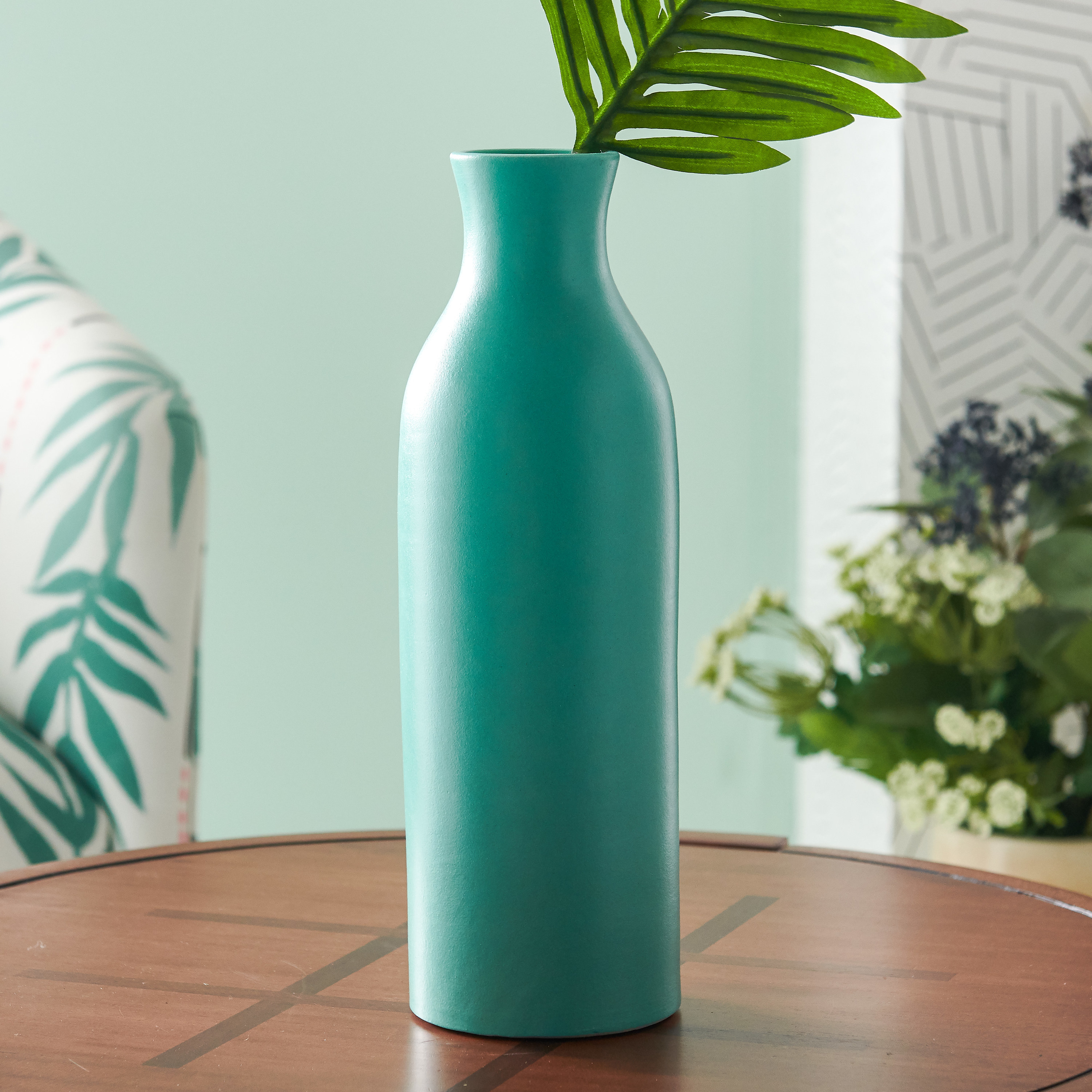 An aqua-colored round, narrow, and tall vase