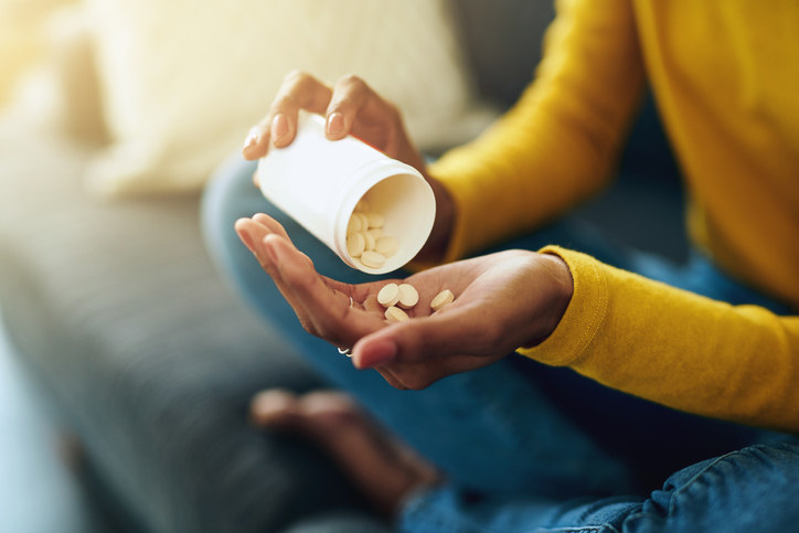 Woman pouring pills into hand.