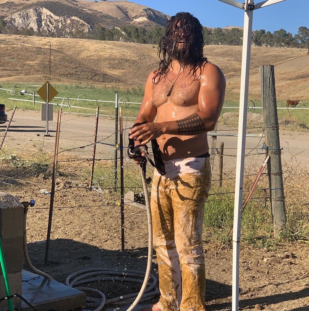 Jason Momoa shirtless and his pants covered in mud